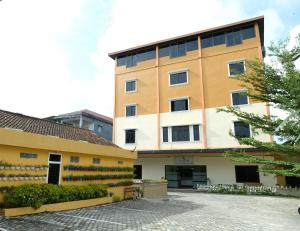 un bâtiment jaune avec des fenêtres latérales dans l'établissement Joyful Hotel, à Tanjung Pandan