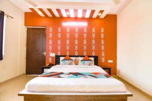 a bedroom with a bed with an orange wall at FabExpress Bzoie Heritage in Dehradun