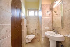 a bathroom with a toilet and a sink and a mirror at FabExpress Bzoie Heritage in Dehradun