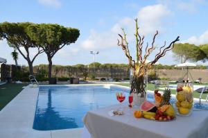 Hotel Albaida Nature في مازاغون: طاولة مع الفاكهة وكؤوس النبيذ بجوار حمام سباحة