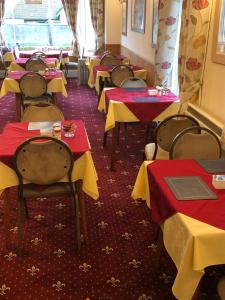 a row of tables in a restaurant with red and yellow tables at Kings Lodge Hotel in Great Yarmouth