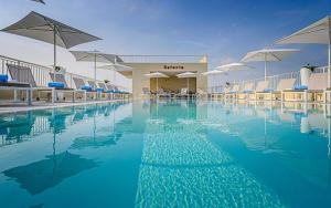 a swimming pool with blue water and umbrellas at Hotel Astoria in Bibione
