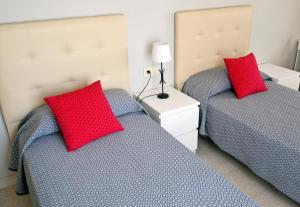 two beds with red pillows in a bedroom at Apartments Kione Playa Romana Park in Alcossebre