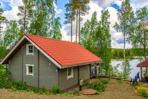 ein kleines Haus mit orangefarbenem Dach neben einem See in der Unterkunft Valteri in Enonkoski