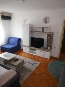 a living room with a blue couch and a tv at Apartman Pero in Kikinda