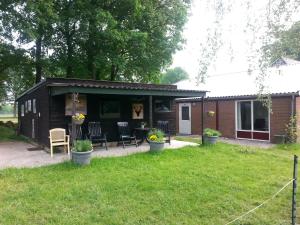 uma pequena cabana com uma mesa e cadeiras num quintal em Wagenschuur em Emst