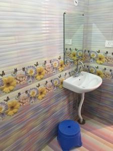 een badkamer met een wastafel en bloemen aan de muur bij HAPPYSTAY rooms and cottages in Ooty