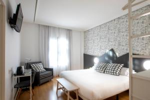 Hotel Urdanibia Park في إرون: غرفة نوم بها سرير أبيض كبير وكرسي