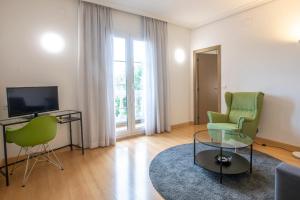 a living room with two green chairs and a television at Hotel Urdanibia Park in Irún