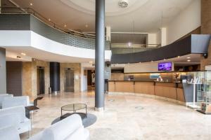 a lobby with white chairs and a tv in a building at Hotel Urdanibia Park in Irún