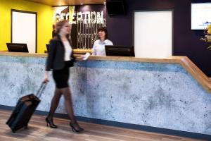 a woman walking past a counter with her luggage at ibis budget London Barking in Barking