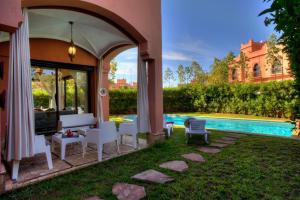 un patio al aire libre con mesa, sillas y piscina en Villa Tilila, en Marrakech