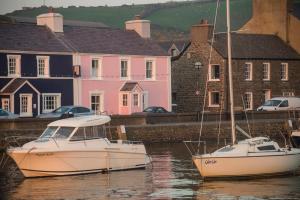 two boats docked in the water in front of houses at Harbourmaster Hotel in Aberaeron