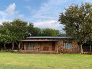 a brick house with a grassy field in front of it at Emmanuel Self-Catering Cottage in Thabazimbi +8 photos