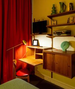 Habitación con escritorio y cortina roja. en Hotel Auberge des Remparts, en Laval