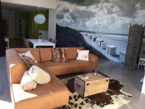 a living room with a brown couch and a beach mural at WELLNESSLOFT in De Haan