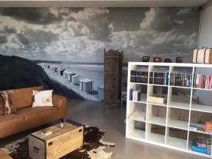 a living room with a couch and a book shelf at WELLNESSLOFT in De Haan
