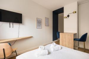 a room with a bed and a tv and chairs at DIFY Charme - Bord du Rhone in Lyon