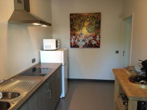 a kitchen with a sink and a white refrigerator at WELLNESSLOFT in De Haan
