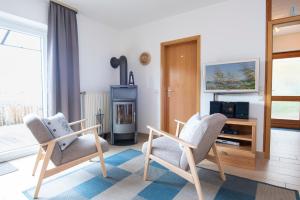 sala de estar con 2 sillas y chimenea en Am Ganterhals 13 Wohnung 1, en Dahme