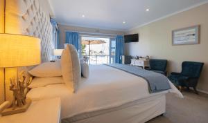 a bedroom with a large bed and a desk and chair at Russells on the Port in Velddrif +43 photos