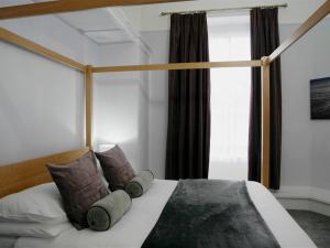 a bedroom with a bed with pillows and a window at Norton House Hotel - Mumbles in Swansea