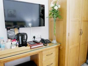 un jarrón de flores sobre una mesa con TV en Norton House Hotel - Mumbles, en Swansea