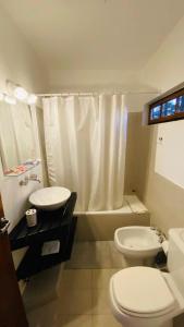 a bathroom with a toilet a sink and a bath tub at Madeo Hotel & Spa in Villa Carlos Paz