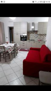 sala de estar con sofá rojo y cocina en Appartamento Ariosto, en Bosa
