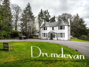 a white house with a bench in front of it at Drumdevan Country House, Inverness in Inverness