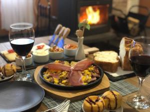 un tavolo con un piatto di cibo e bicchieri di vino di Guest House Durmitor Paradise a Žabljak