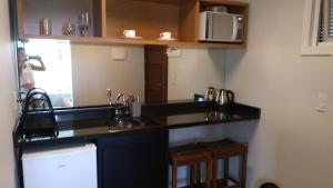 a kitchen with a black counter and a microwave at Pousada Las Piedras in Praia do Rosa