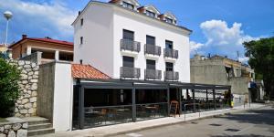 een groot wit gebouw met een restaurant ervoor bij Azur in Novi Vinodolski
