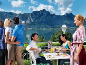 un grupo de personas de pie alrededor de una mesa en un patio en Landzeit Motor-Hotel Mondsee, en Mondsee