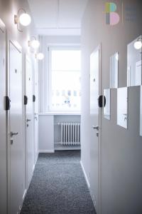 a hallway with white doors and a window at Kapsuły Bello ApartHostel in Warsaw