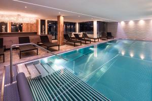 a swimming pool in a hotel with chairs and tables at URSPRUNG Panorama Hotel Königsleiten in Königsleiten