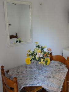 a dining room table with a vase of flowers on it at Eleni's Rooms in Loutra Edipsou