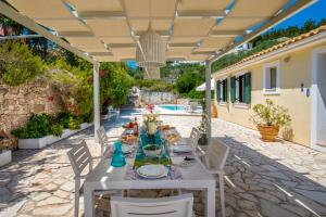 a white table and chairs on a patio with a pool at Villa Sofia in Gaios
