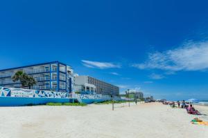 uma praia com um edifício e pessoas sentadas na areia em Chateau Mar Beach Resort em Ormond Beach