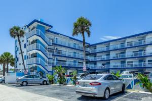 um edifício de apartamentos azul com dois carros estacionados num parque de estacionamento em Chateau Mar Beach Resort em Ormond Beach