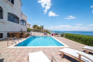 una piscina di fronte a una casa con l'oceano di Apartments Grlica a Sutivan (San Giovanni di Brazza)