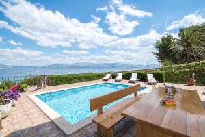a swimming pool with a wooden table and chairs next to at Apartments Grlica in Sutivan