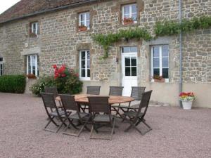 a wooden table and chairs in front of a building at GITE Les Aubues in Lormes