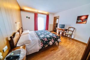 a bedroom with a bed and a desk with a computer at Hotel Valgioconda in Sappada