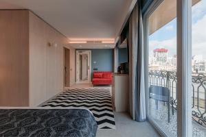1 dormitorio con balcón y sofá rojo en 123 MAINSTREET boutique hotel en St Julian's