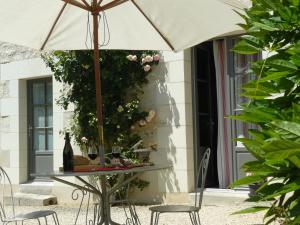 a table with a bottle of wine and an umbrella at Chambres d'hôtes Rue du Poids in Bourgueil