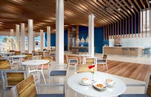 a restaurant with white tables and chairs and blue walls at The Morgan Resort Spa & Village in Simpson Bay