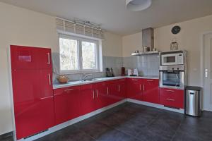 een rode keuken met rode kasten en een raam bij Maison Violette in Durbuy