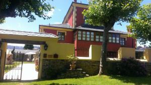 una casa roja y amarilla con un árbol en el patio en Casa do Merlo, en Barreiros