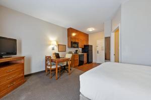 Extended Stay America Suites - Lawton - Fort Sill في لوتون: غرفة نوم بسرير ومكتب مع تلفزيون